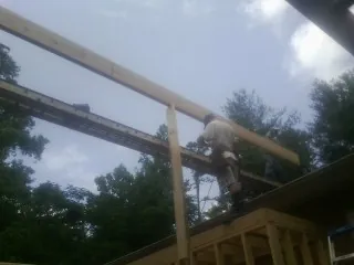 Carpenter setting a ridge beam over a new addition frame — Ice Dam Removal by Roofing Brothers in Atkinson
