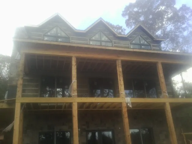 Dormers and porch framing on a large log home under construction — Roof Coating work by our crew in Atkinson